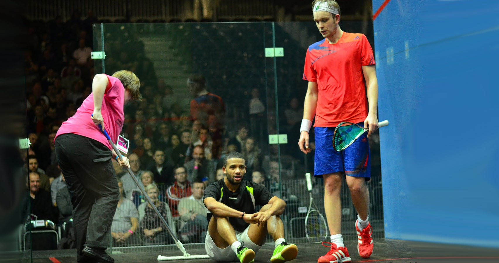 A volunteer sweeping during a James Willstrop match