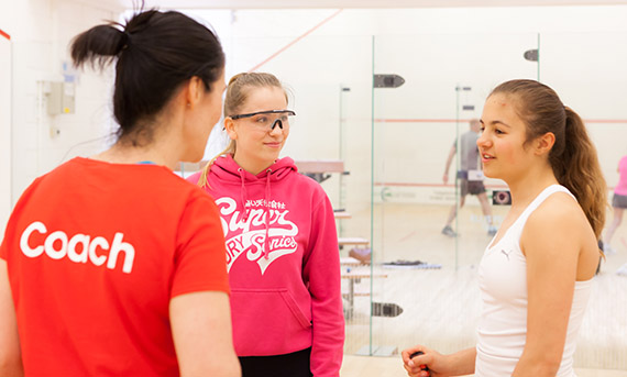 Squash coach with two young female players