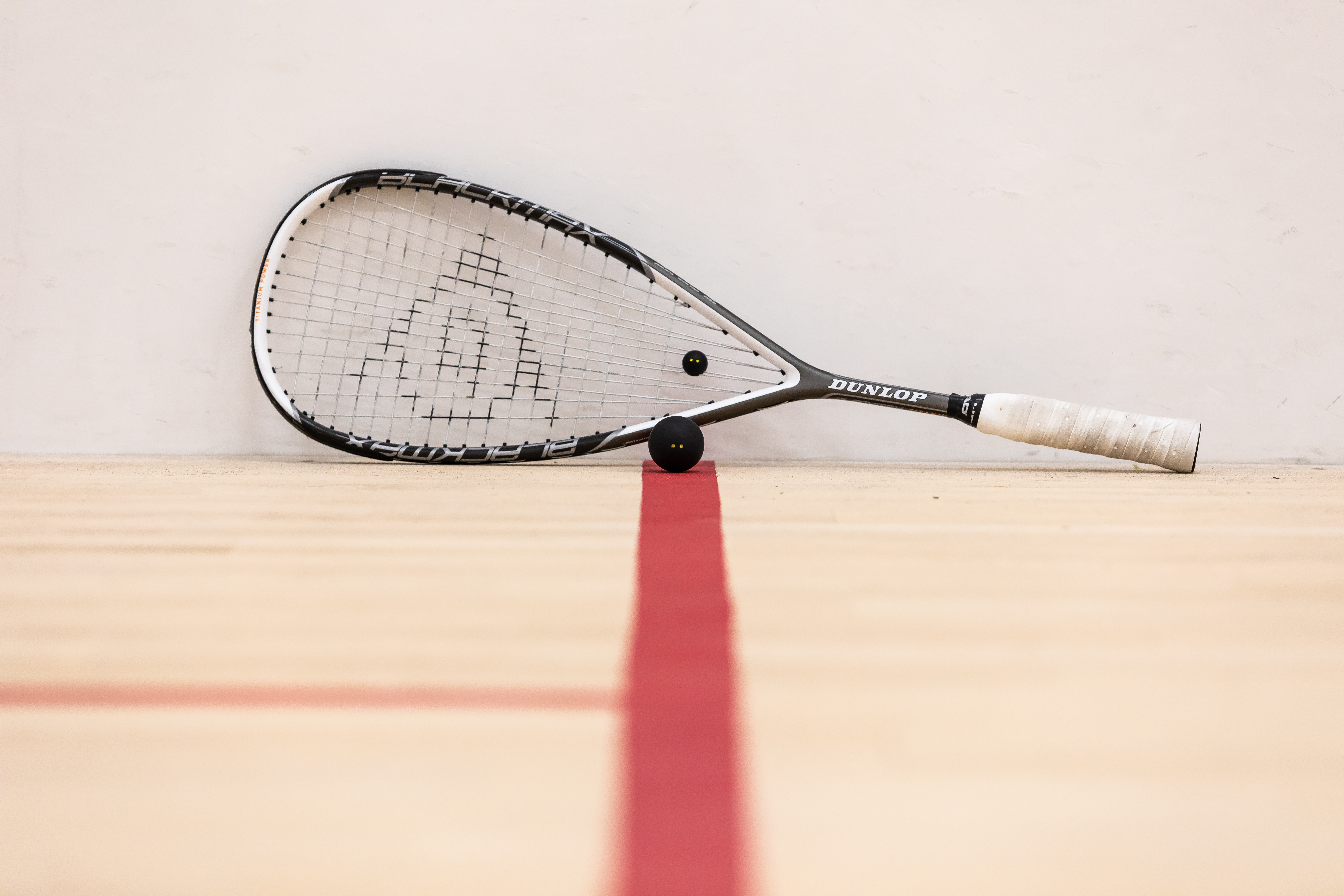 A squash racket and a ball on a court