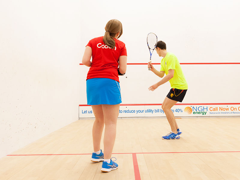 Female squash coach coaching a young male