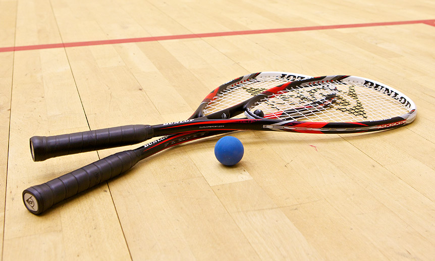 Two squash rackets and a ball on a court